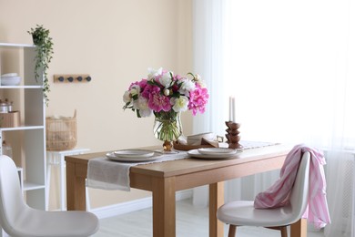 Photo of Beautiful table setting with bouquet of peonies in dining room. Interior design
