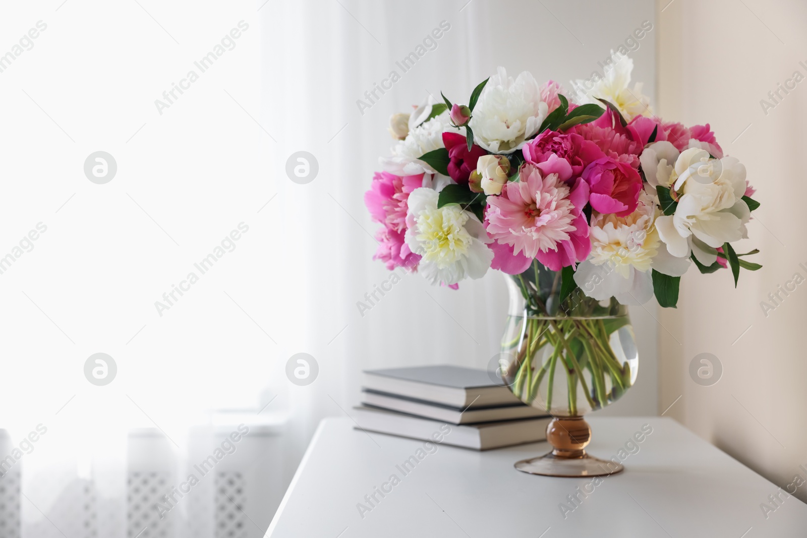 Bouquet of beautiful peonies and books on white table indoors, space for text. Interior design Photo of Bouquet of beautiful peonies and books on white table indoors, space for text. Interior design