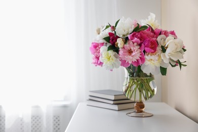 Photo of Bouquet of beautiful peonies and books on white table indoors, space for text. Interior design