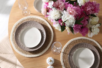 Photo of Beautiful table setting with bouquet of peonies indoors, top view