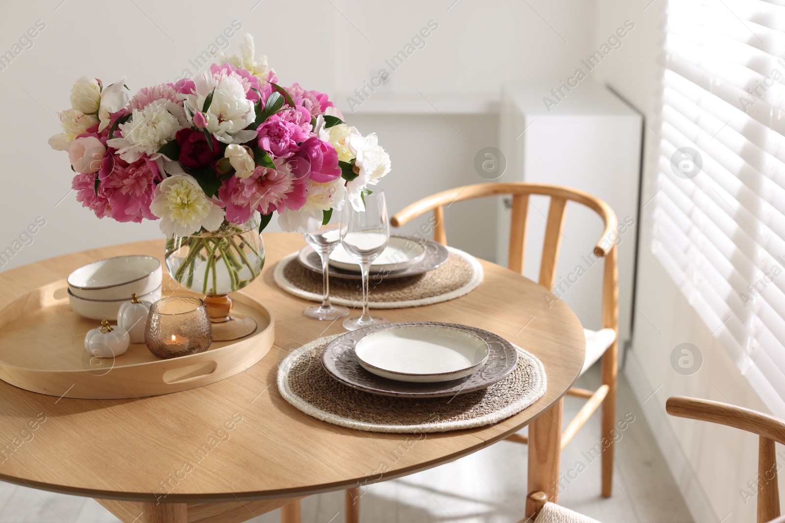 Beautiful table setting with bouquet of peonies in dining room, closeup Photo of Beautiful table setting with bouquet of peonies in dining room, closeup