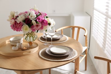 Photo of Beautiful table setting with bouquet of peonies in dining room, closeup