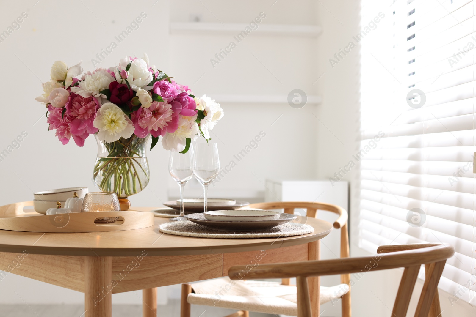 Beautiful table setting with bouquet of peonies in dining room. Space for text Photo of Beautiful table setting with bouquet of peonies in dining room. Space for text