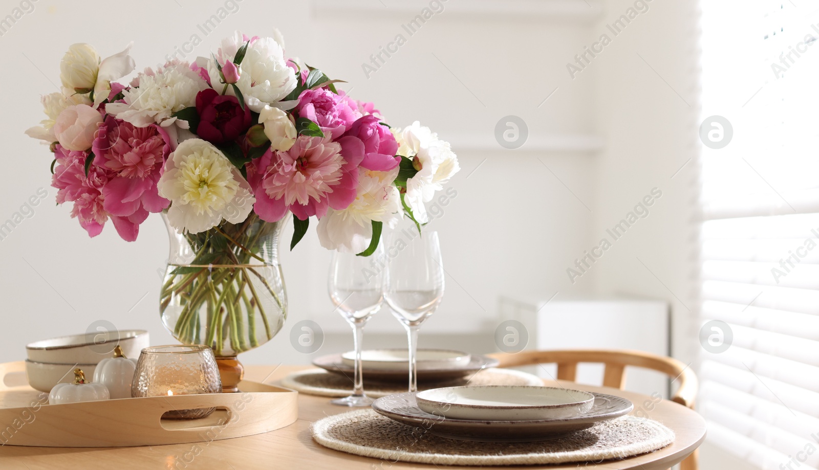 Beautiful table setting with bouquet of peonies in dining room, closeup. Space for text Photo of Beautiful table setting with bouquet of peonies in dining room, closeup. Space for text