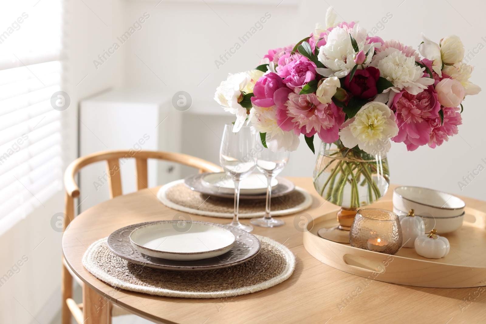 Beautiful table setting with bouquet of peonies in dining room, closeup Photo of Beautiful table setting with bouquet of peonies in dining room, closeup