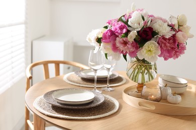 Photo of Beautiful table setting with bouquet of peonies in dining room, closeup
