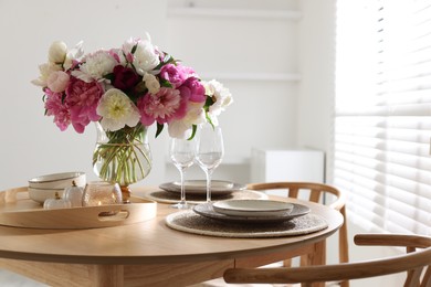 Photo of Beautiful table setting with bouquet of peonies in dining room. Space for text