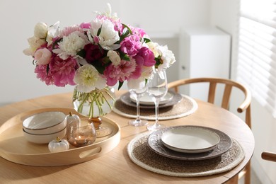 Photo of Beautiful table setting with bouquet of peonies in dining room, closeup