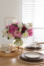 Photo of Beautiful table setting with bouquet of peonies in dining room, closeup