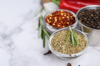 Photo of Different aromatic spices on white marble table, closeup. Space for text