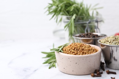 Photo of Different aromatic spices on white marble table, closeup. Space for text