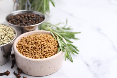 Photo of Different aromatic spices on white marble table, closeup. Space for text