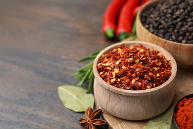 Photo of Different aromatic spices on wooden table, closeup. Space for text
