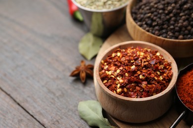 Photo of Different aromatic spices on wooden table, closeup. Space for text