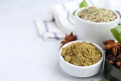 Photo of Different aromatic spices on white tiled table, closeup. Space for text