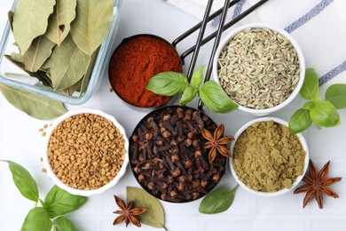 Photo of Different aromatic spices on white tiled table, flat lay