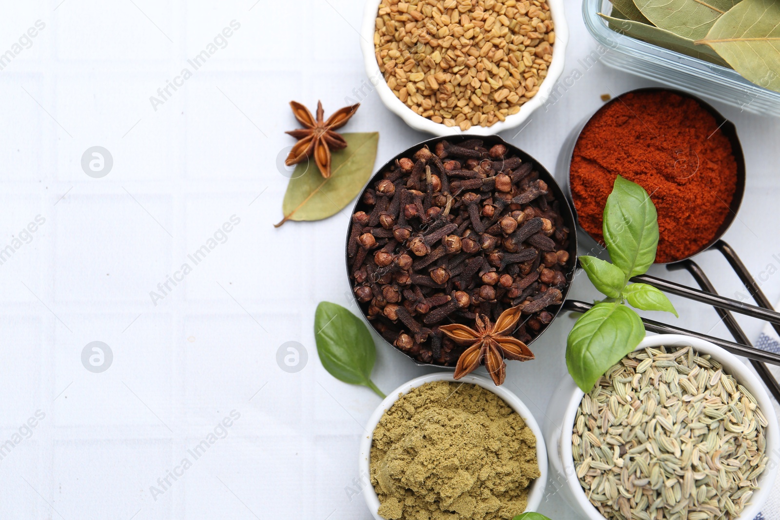 Different aromatic spices on white tiled table, flat lay. Space for text Photo of Different aromatic spices on white tiled table, flat lay. Space for text