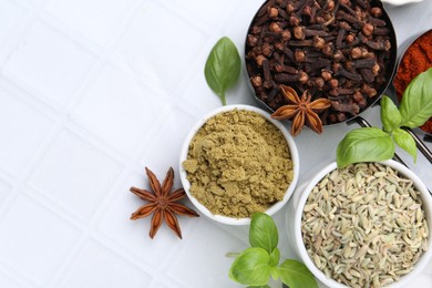 Photo of Different aromatic spices on white tiled table, flat lay. Space for text