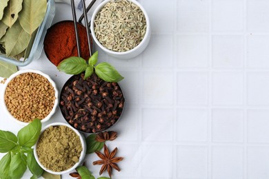 Photo of Different aromatic spices on white tiled table, flat lay. Space for text