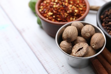 Photo of Different aromatic spices on white wooden table, closeup. Space for text
