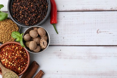 Photo of Different aromatic spices on white wooden table, flat lay. Space for text