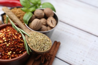 Photo of Different aromatic spices on white wooden table, closeup. Space for text