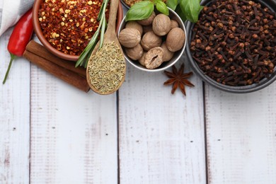 Photo of Different aromatic spices on white wooden table, flat lay. Space for text