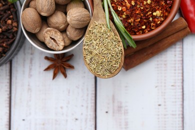Photo of Different aromatic spices on white wooden table, flat lay. Space for text