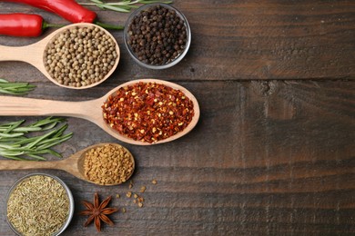 Photo of Different aromatic spices on wooden table, flat lay. Space for text