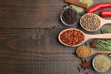 Photo of Different aromatic spices on wooden table, flat lay. Space for text