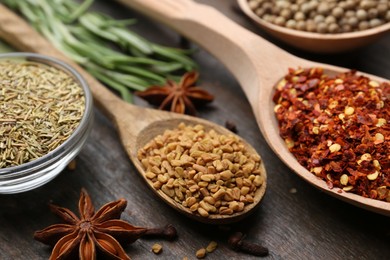 Photo of Different aromatic spices on wooden table, closeup