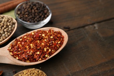 Photo of Different aromatic spices on wooden table, closeup. Space for text