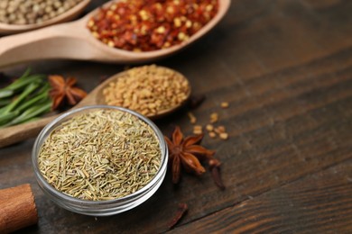 Photo of Different aromatic spices on wooden table, closeup. Space for text