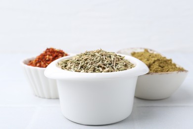 Photo of Different aromatic spices on white tiled table, closeup