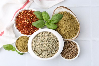 Photo of Different aromatic spices on white tiled table, flat lay