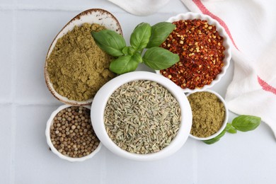 Photo of Different aromatic spices on white tiled table, flat lay