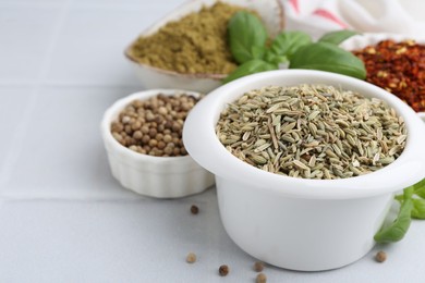 Photo of Different aromatic spices on white tiled table, closeup