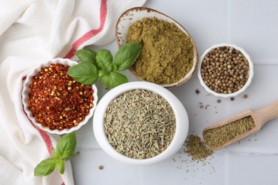 Photo of Different aromatic spices on white tiled table, flat lay