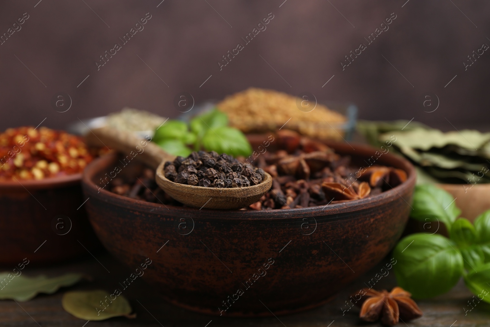 Different aromatic spices on wooden table against brown background, closeup Photo of Different aromatic spices on wooden table against brown background, closeup
