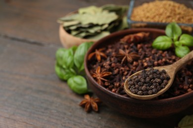 Photo of Different aromatic spices on wooden table, closeup. Space for text