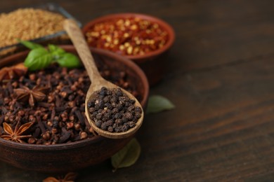 Photo of Different aromatic spices on wooden table, closeup. Space for text