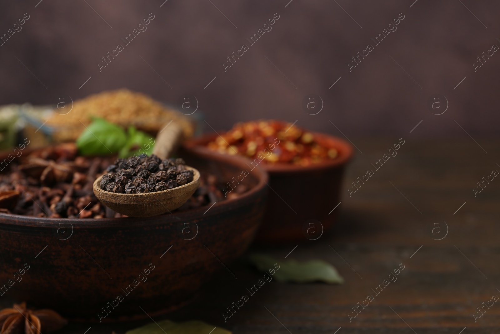 Different aromatic spices on wooden table against brown background, closeup. Space for text Photo of Different aromatic spices on wooden table against brown background, closeup. Space for text