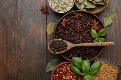 Photo of Different aromatic spices on wooden table, flat lay. Space for text