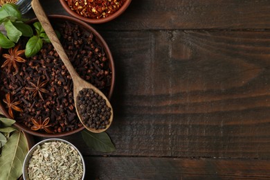 Photo of Different aromatic spices on wooden table, flat lay. Space for text