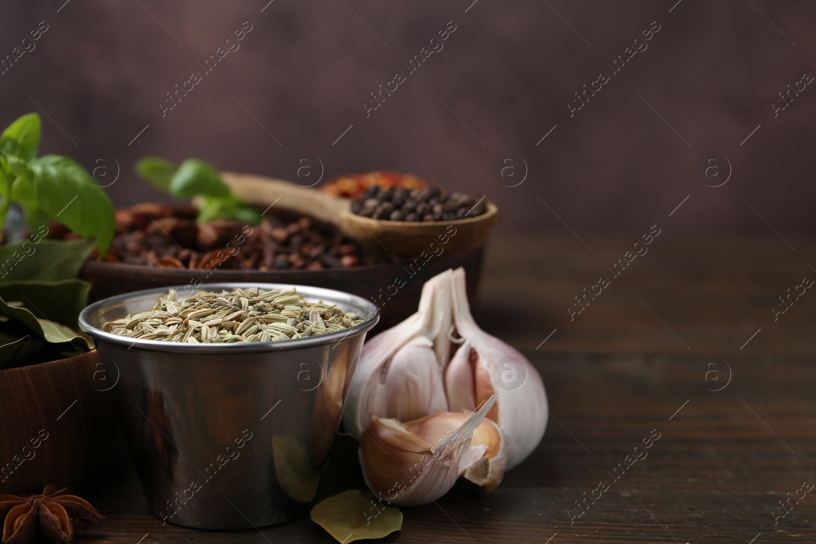 Different aromatic spices on wooden table against brown background, closeup. Space for text Photo of Different aromatic spices on wooden table against brown background, closeup. Space for text