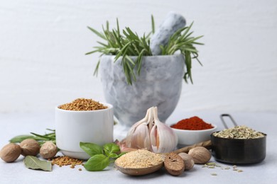 Photo of Different aromatic spices on grey table against light background, closeup