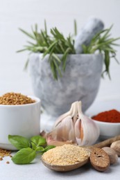 Photo of Different aromatic spices on grey table against light background, closeup