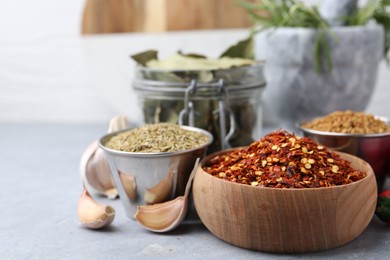 Photo of Different aromatic spices on grey table against light background, closeup