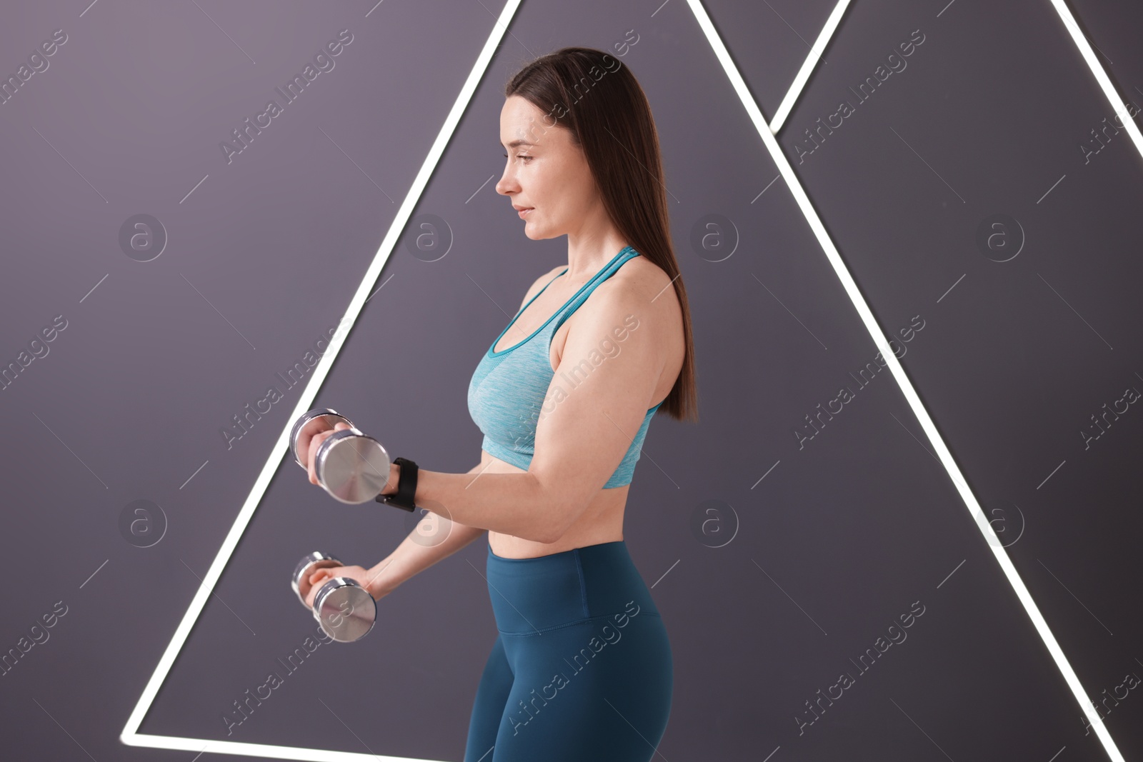 Woman exercising with dumbbells in fitness studio Photo of Woman exercising with dumbbells in fitness studio