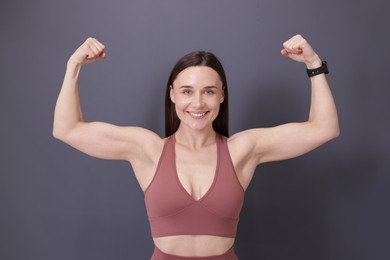 Photo of Woman in fitness clothes showing her biceps on grey background